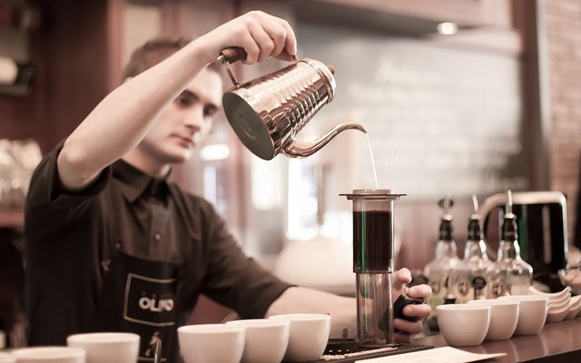 With great care and attention, a barista makes coffee
